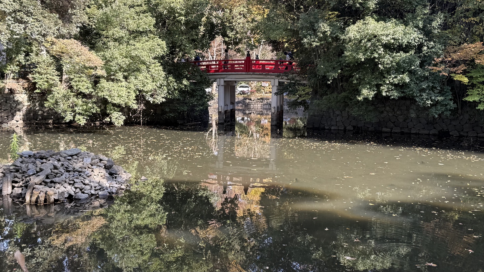 A vermilion bridge over a pond on the grounds