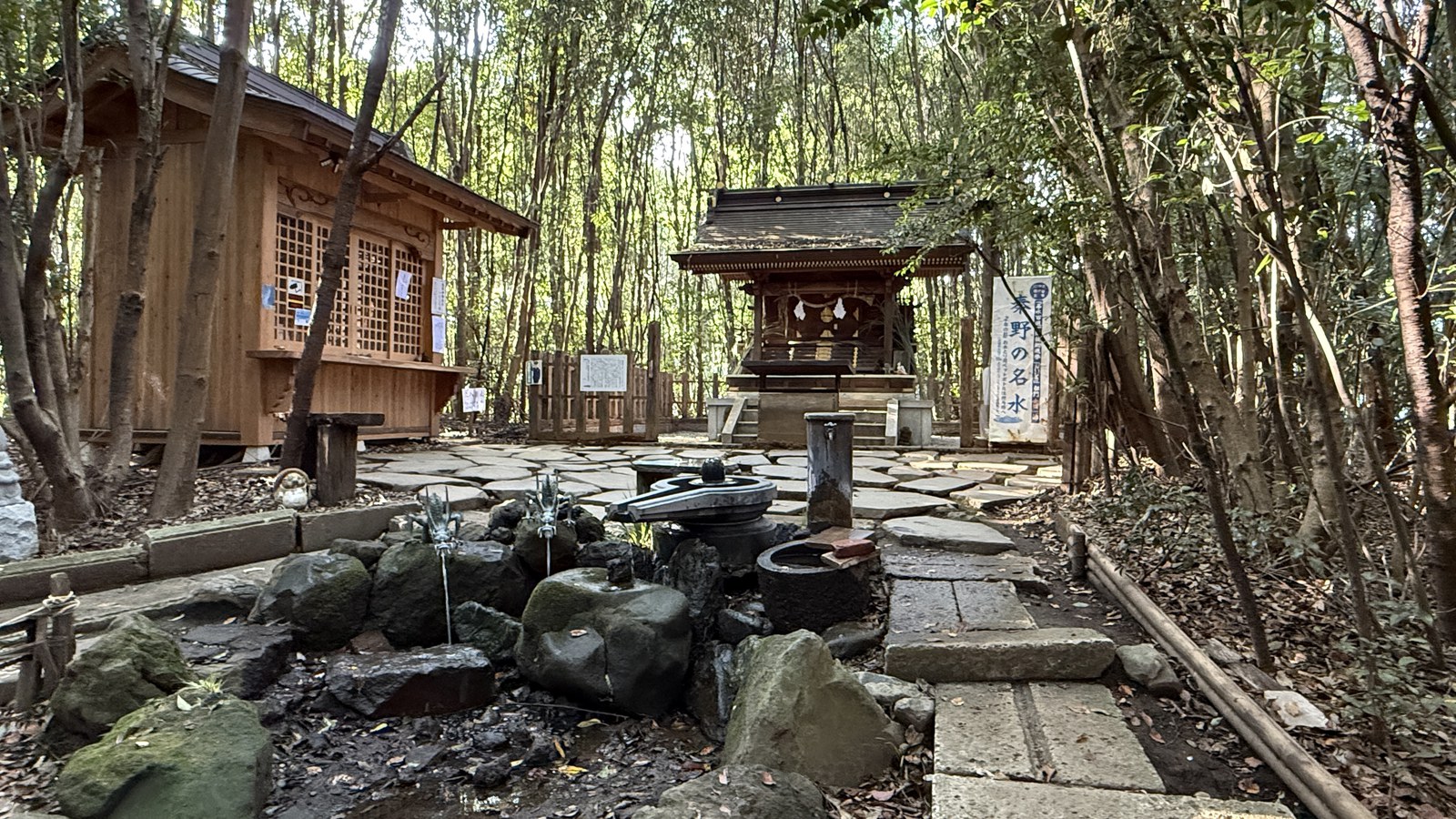 Spring water among stones, with small shrines beyond