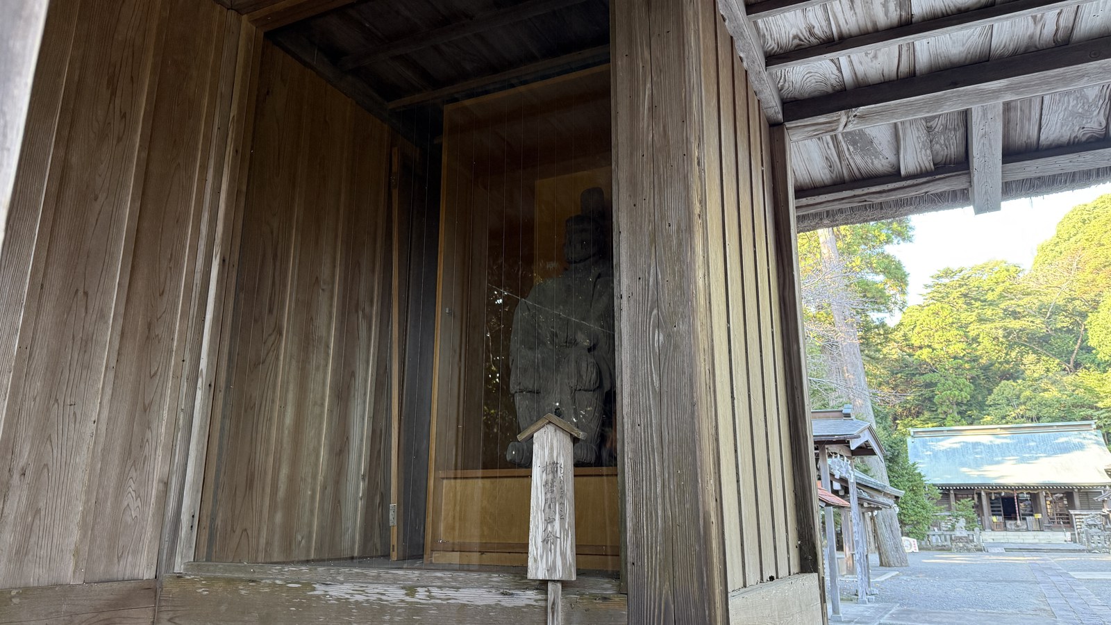 A statue in a wooden shelter beside the path