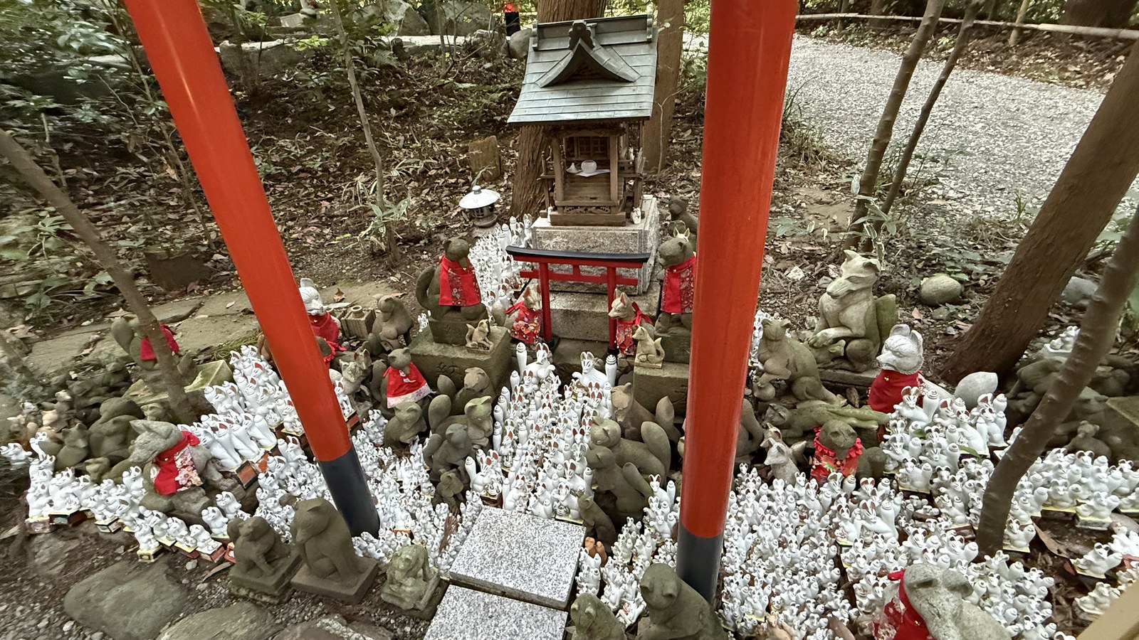 Countless small white foxes between the pillars of a vermilion torii