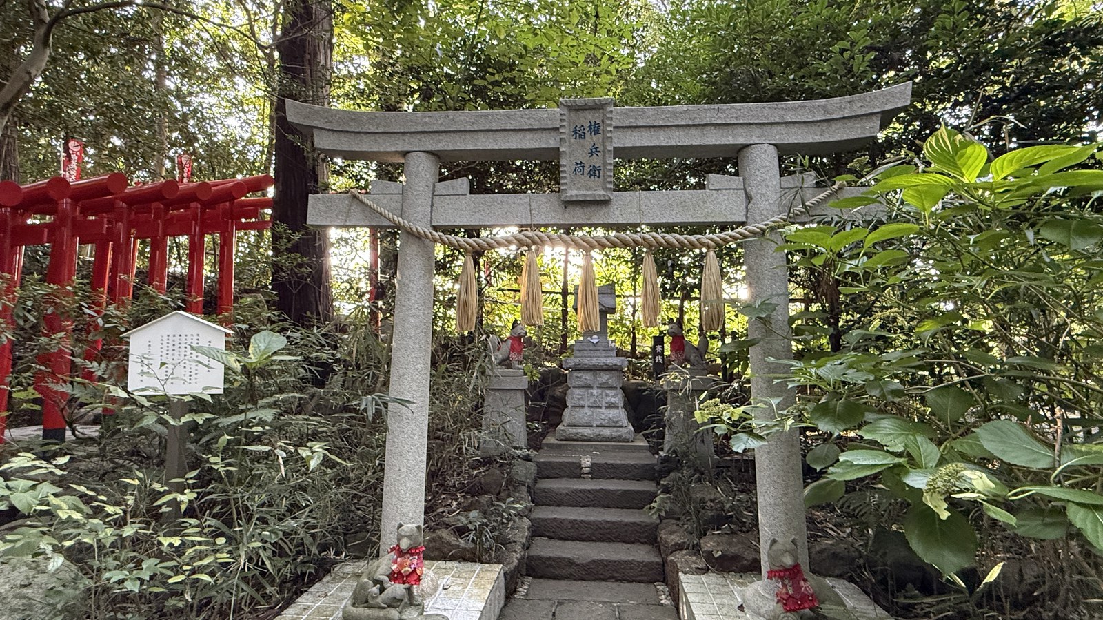 A stone torii, with small fox statues at its base