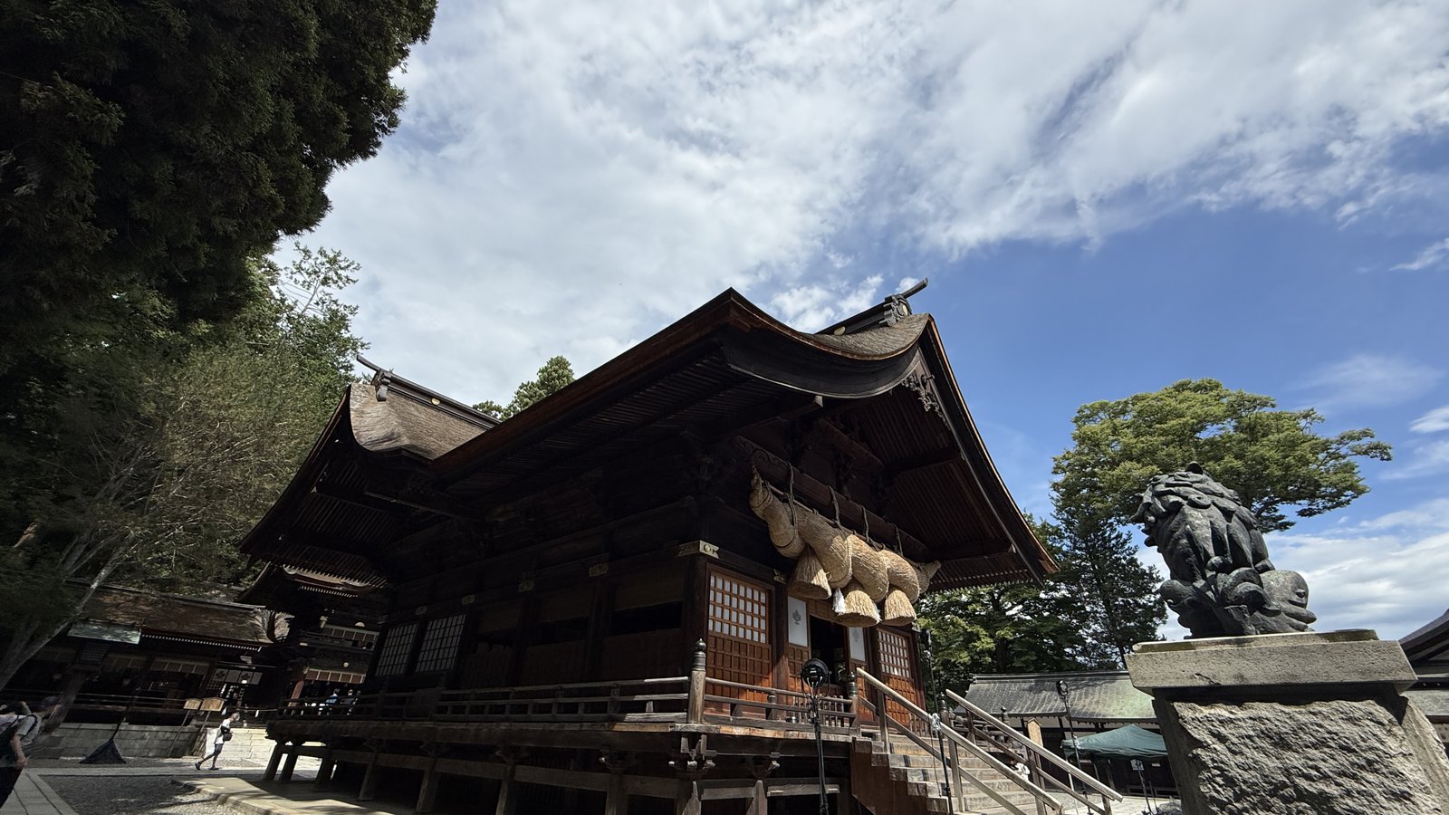 A building hung with a large shimenawa, and a komainu